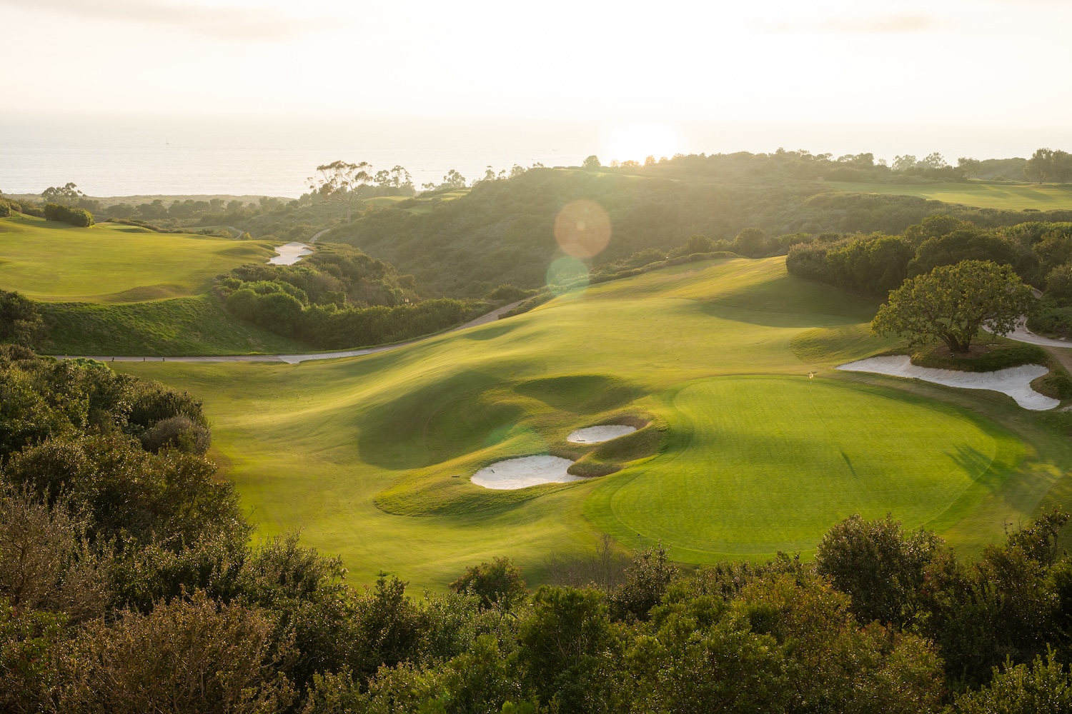aerial shot during sunset of a golf hole at pelican hill resort in newport california with the pacific ocean in the background